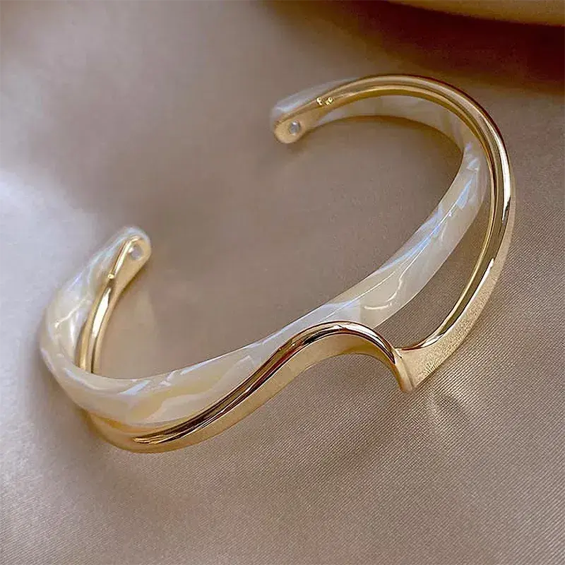 Pulsera abierta con esmalte blanco y acabado dorado